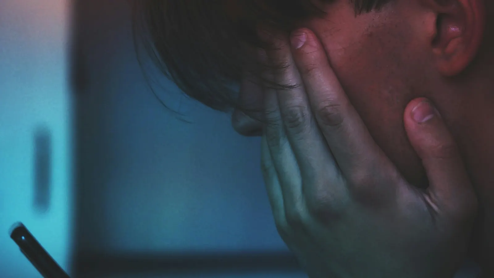 Una persona con lo smartphone in mano e il volto tra le mani