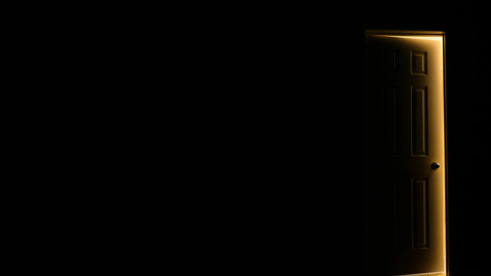 Una porta aperta da cui entra luce in una stanza buia