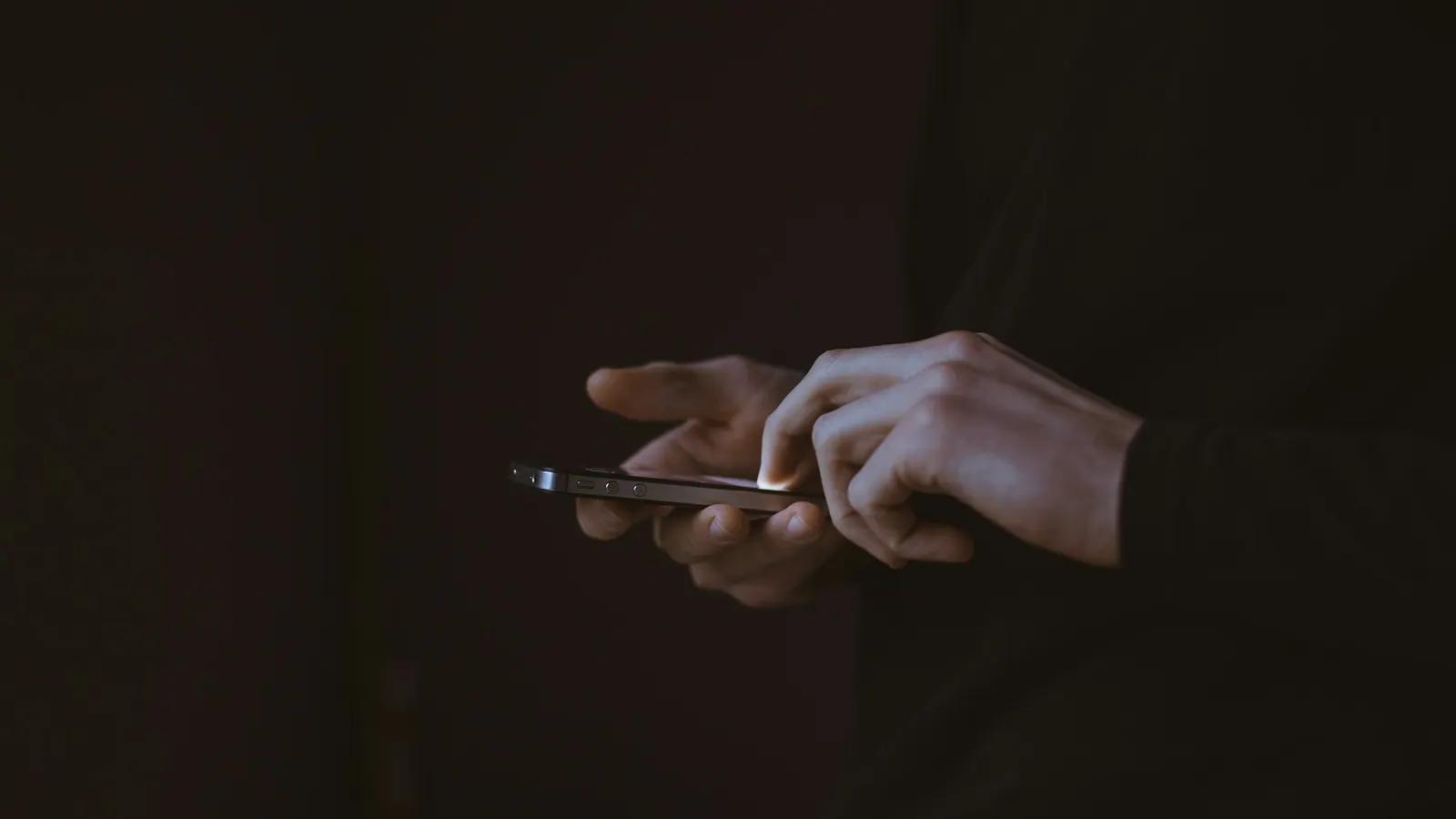 Una persona al buio che scorre lo smartphone
