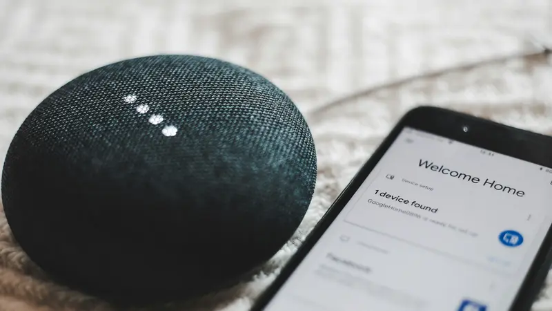 Uno smart speaker acceso accanto a uno smartphone