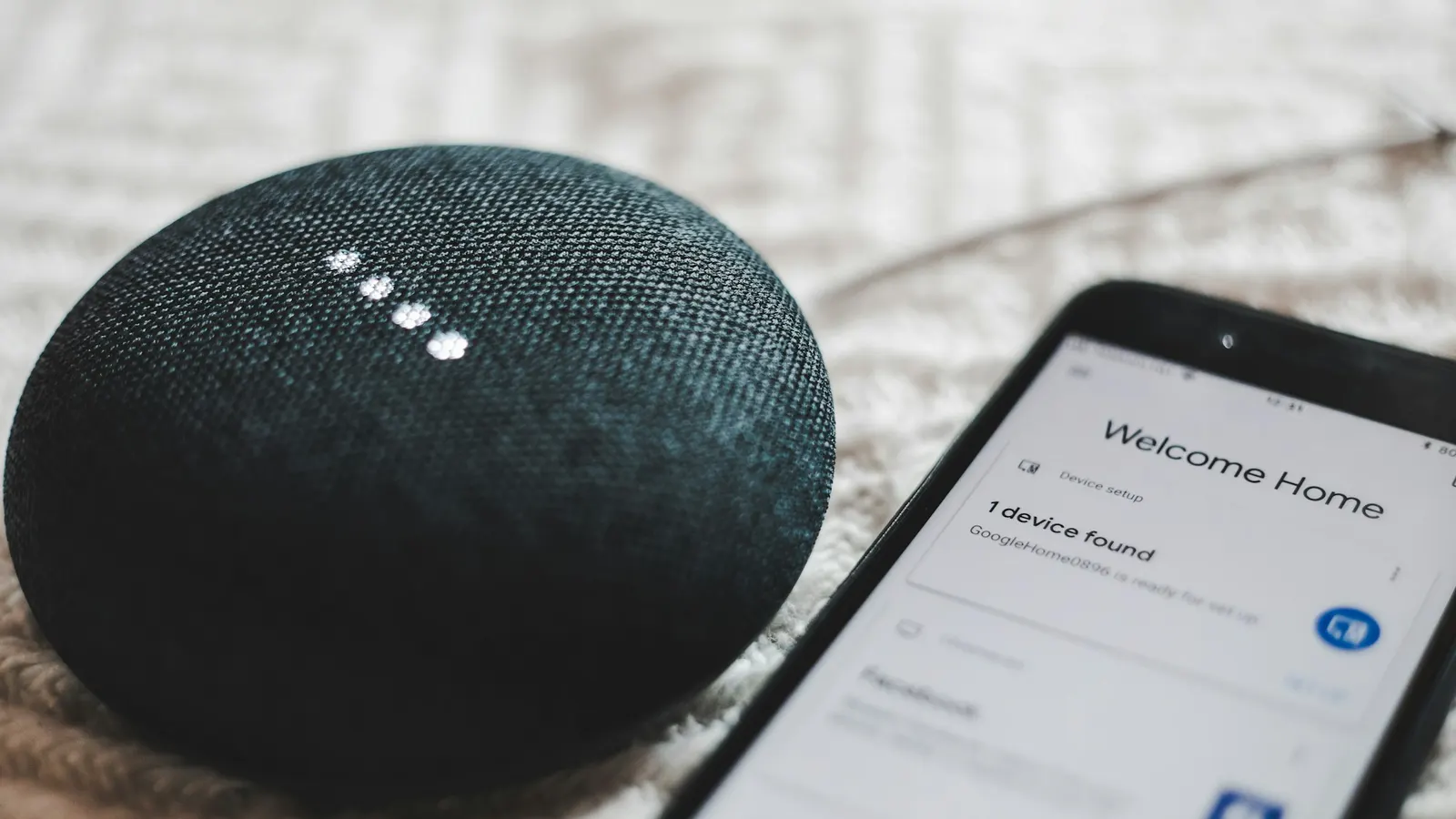 Uno smart speaker acceso accanto a uno smartphone